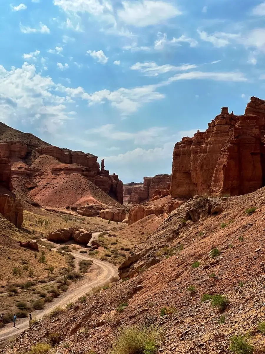 Winding dirt trail through the towering red rock spires of the Valley of Castles with small figures of hikers